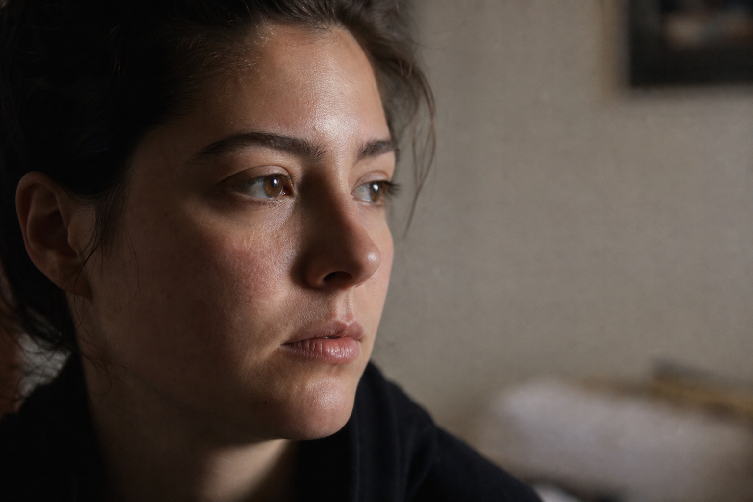 Person's face in diffused morning window light, flushed cheeks visible, shallow depth of field, quiet domestic interior